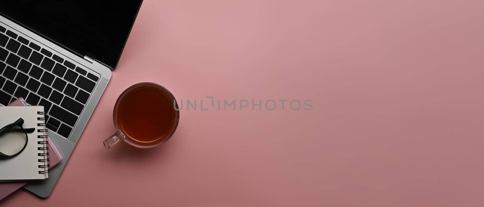 Coffee cup, laptop computer and notebook on pink background with copy space.