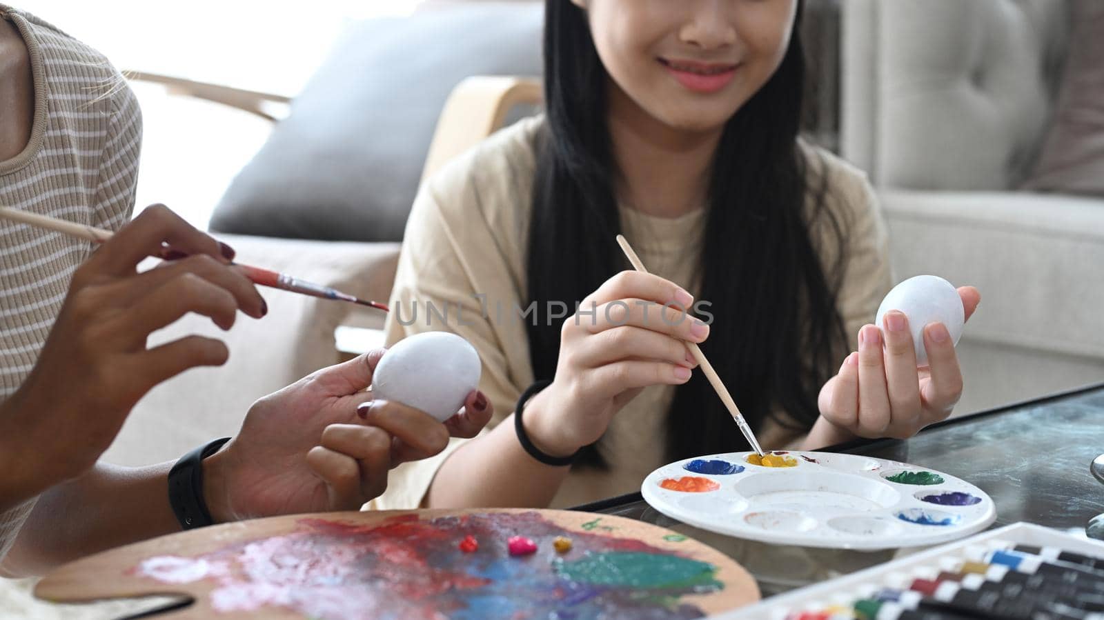 Happy girl coloring Easter eggs with watercolors. Easter holidays concept. by prathanchorruangsak