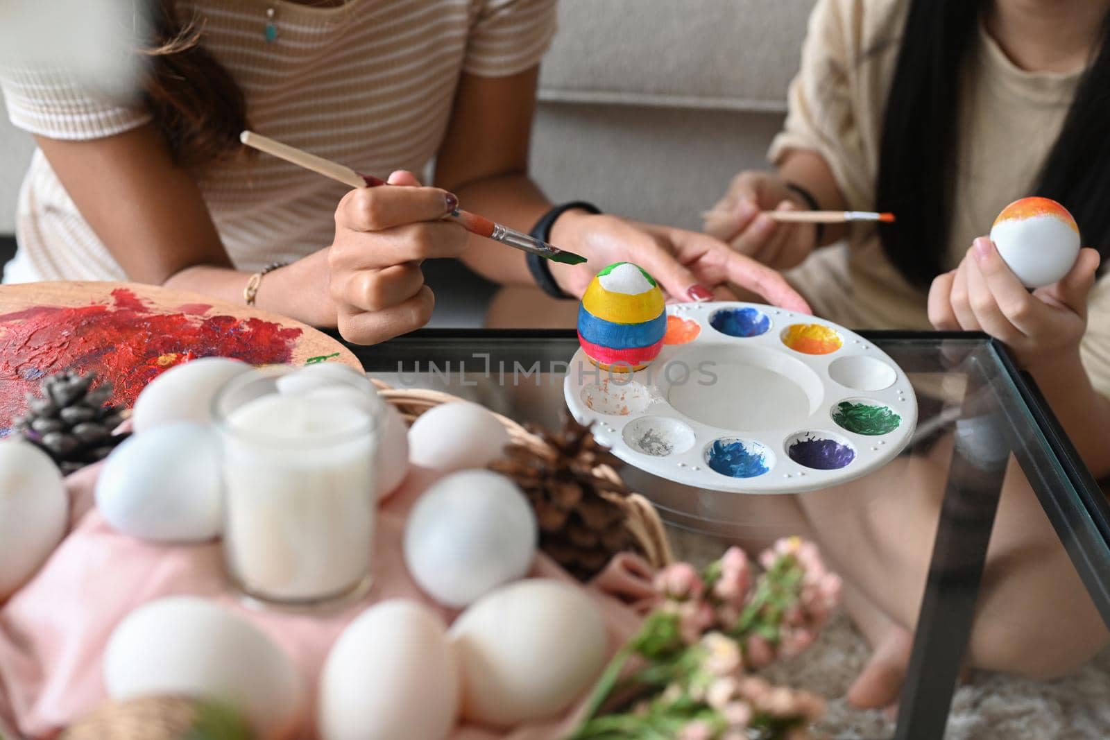 Child and mother hand painting Easter egg with paintbrush. Easter holidays and people concept. by prathanchorruangsak