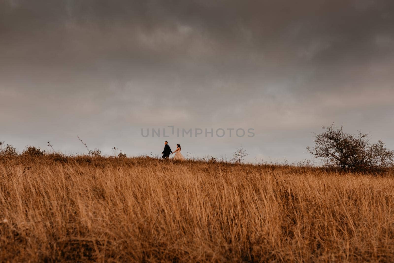 silhouettes of man and a woman against the backdrop of a formidable sky by AndriiDrachuk