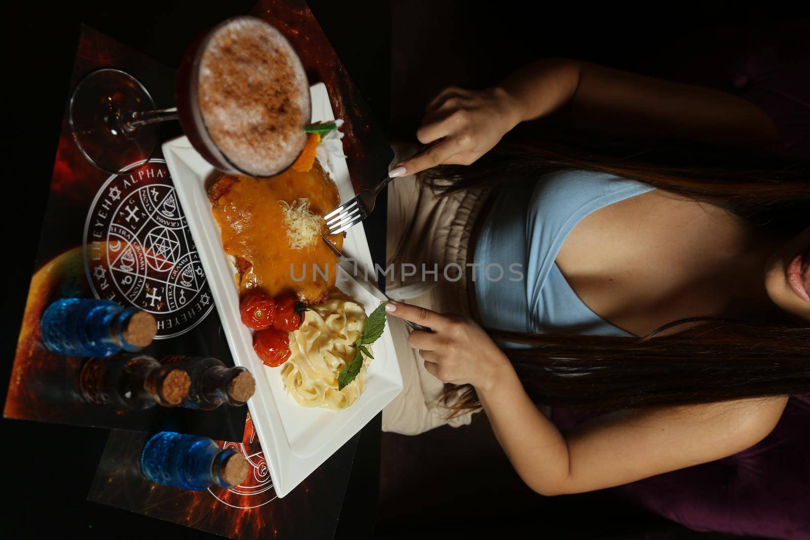 young woman eating with food in restaurant