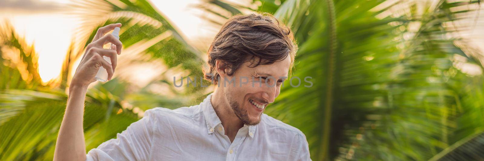 Young man spraying mosquito insect repellent in the forrest, insect protection BANNER, LONG FORMAT by galitskaya