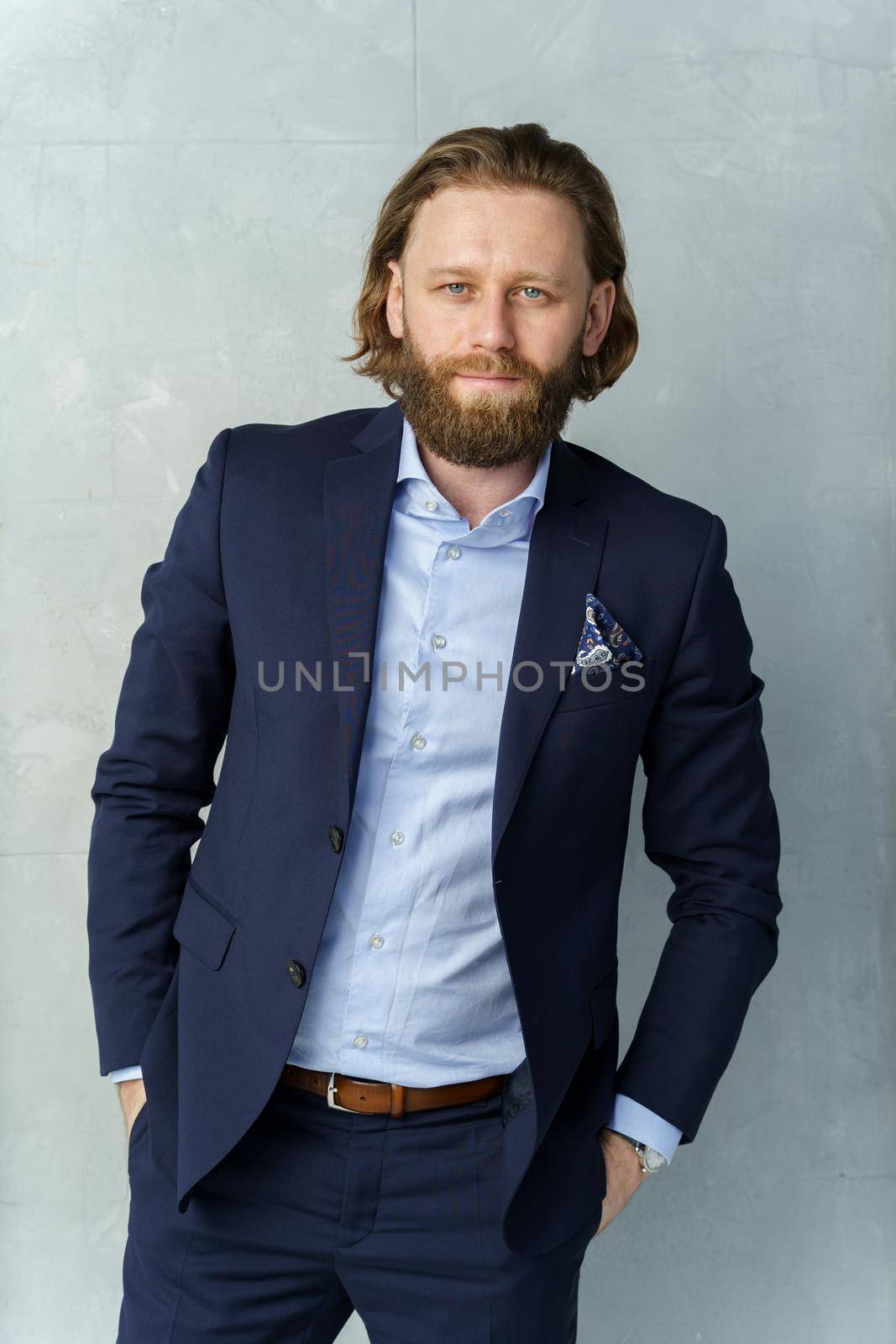 a handsome brutal bearded and long-haired man, a stylish businessman on a white background. High quality photo