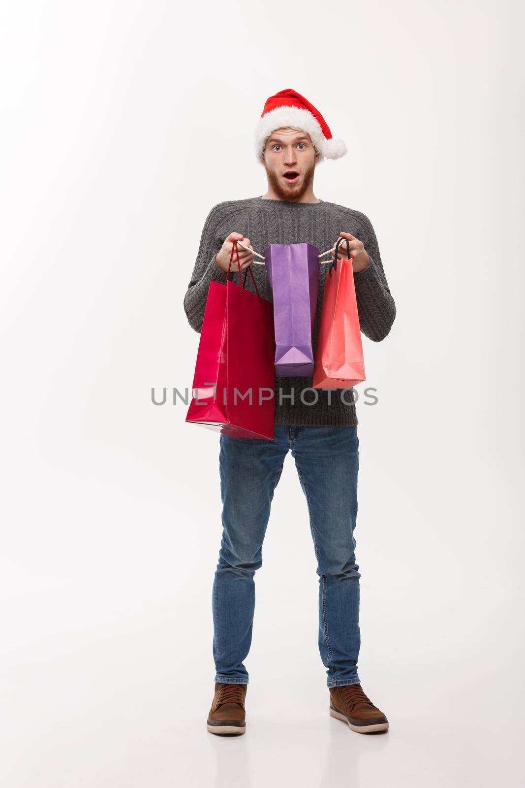 Christmas Concept - attractive young caucasian man surprising shocking gift in shopping bag.