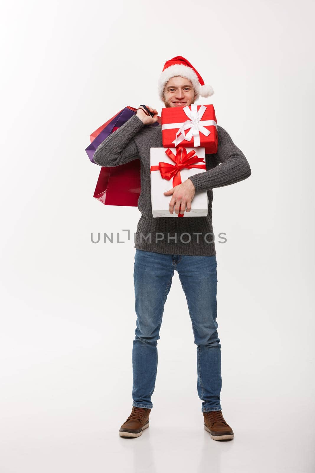 Christmas Concept - attractive young caucasian man enjoy shopping holding a lot of presents in Christmas Day. by Benzoix