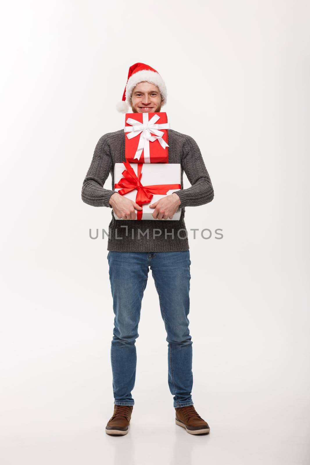 Christmas Concept - Happy young man with beard carries a lot of presents isolated on white background.