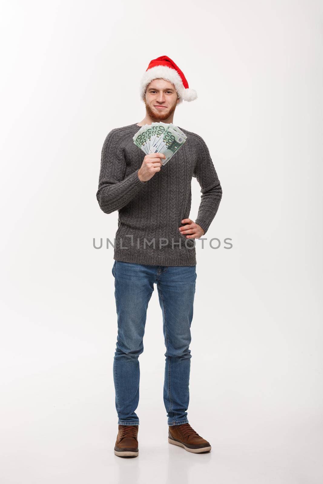 Holiday Concept - Young beard man in sweater showing money to camera.