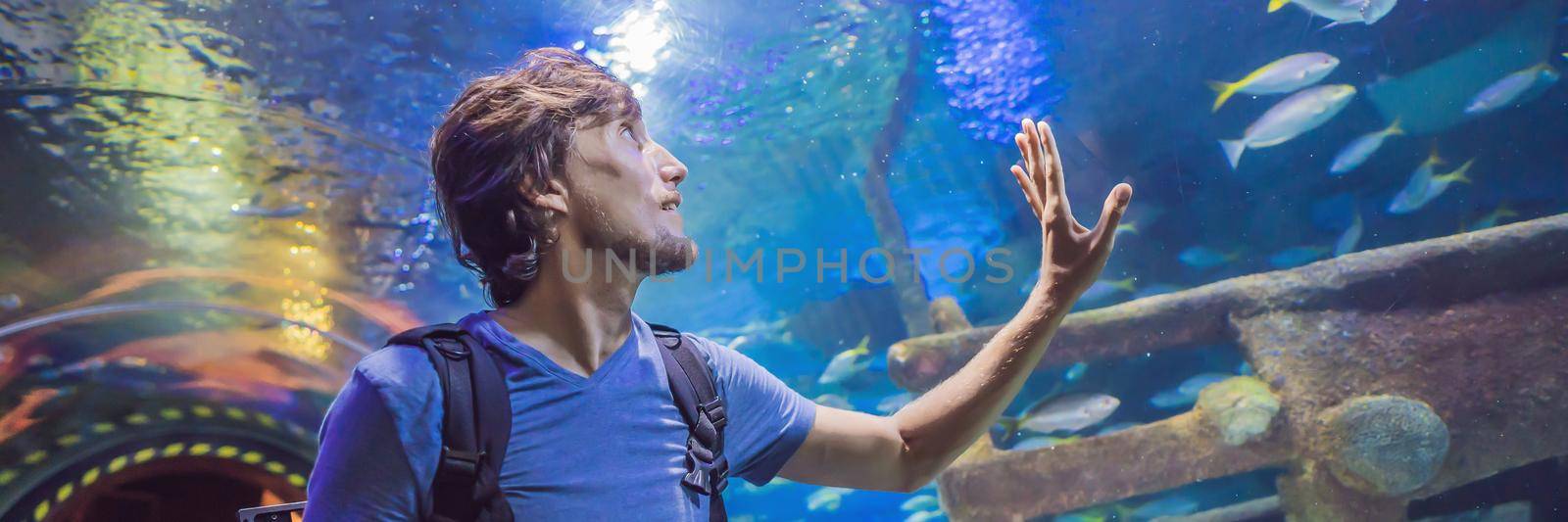 curious tourist watching with interest on shark in oceanarium tunnel. BANNER, LONG FORMAT