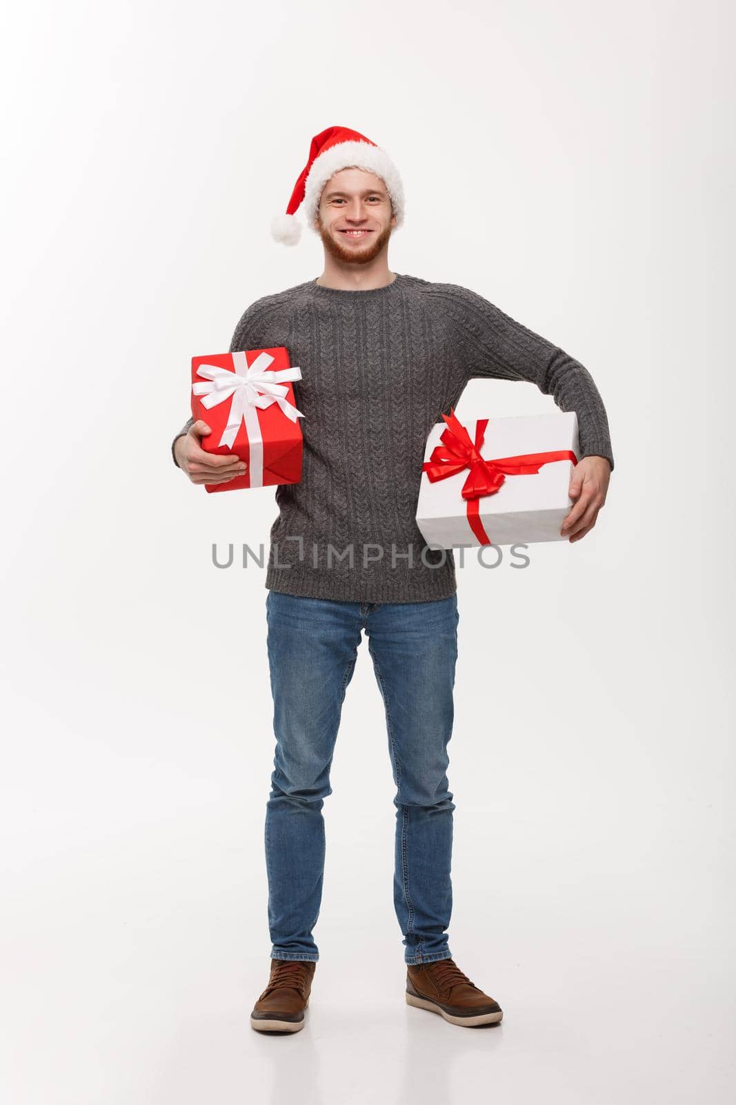 Christmas Concept - Happy young man with beard carries a lot of presents isolated on white background.