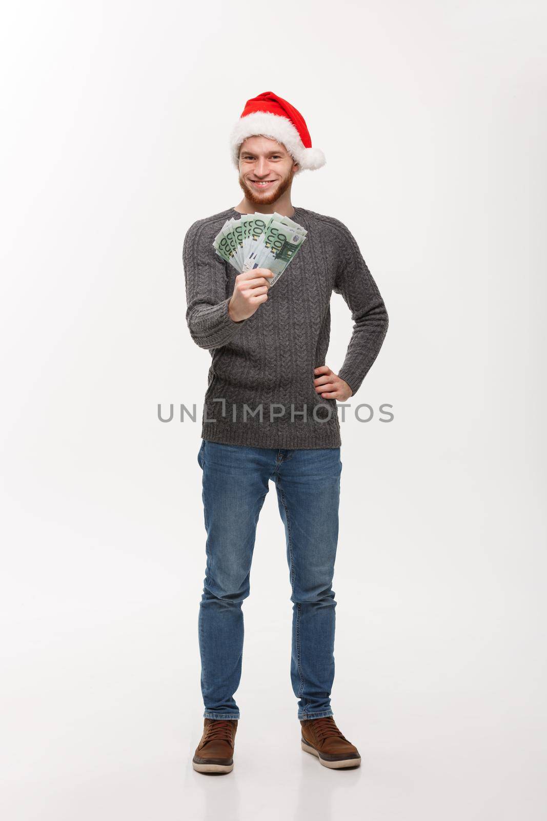 Holiday Concept - Young beard man in sweater showing money to camera.