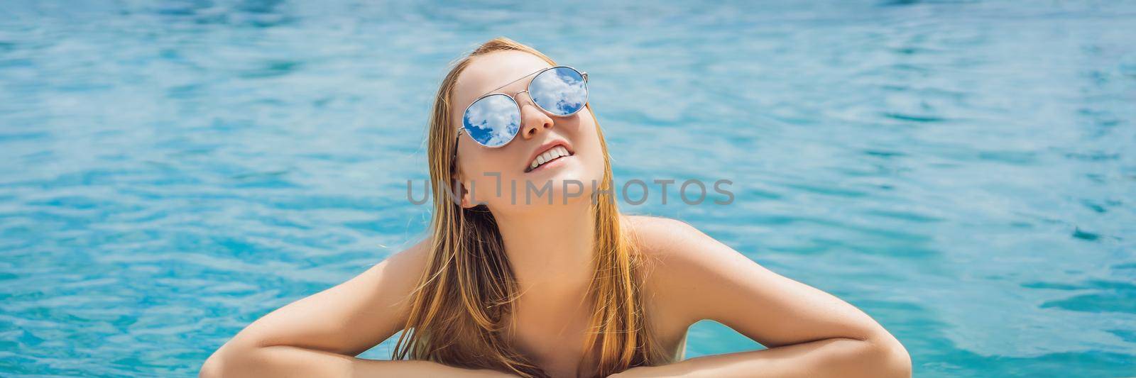 Young woman in outdoor swimming pool with city view in blue sky. BANNER, LONG FORMAT