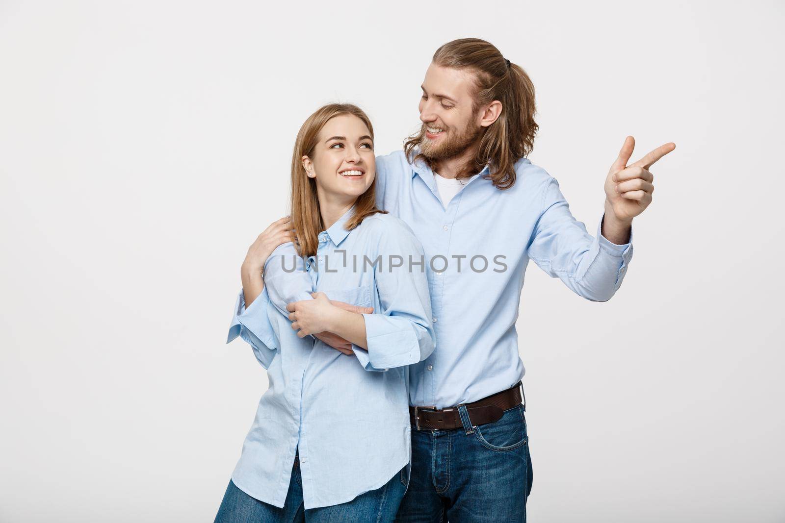 Portrait young happy couple love smiling embracing point finger to empty copy space, man and woman smile looking up, isolated over white background by Benzoix