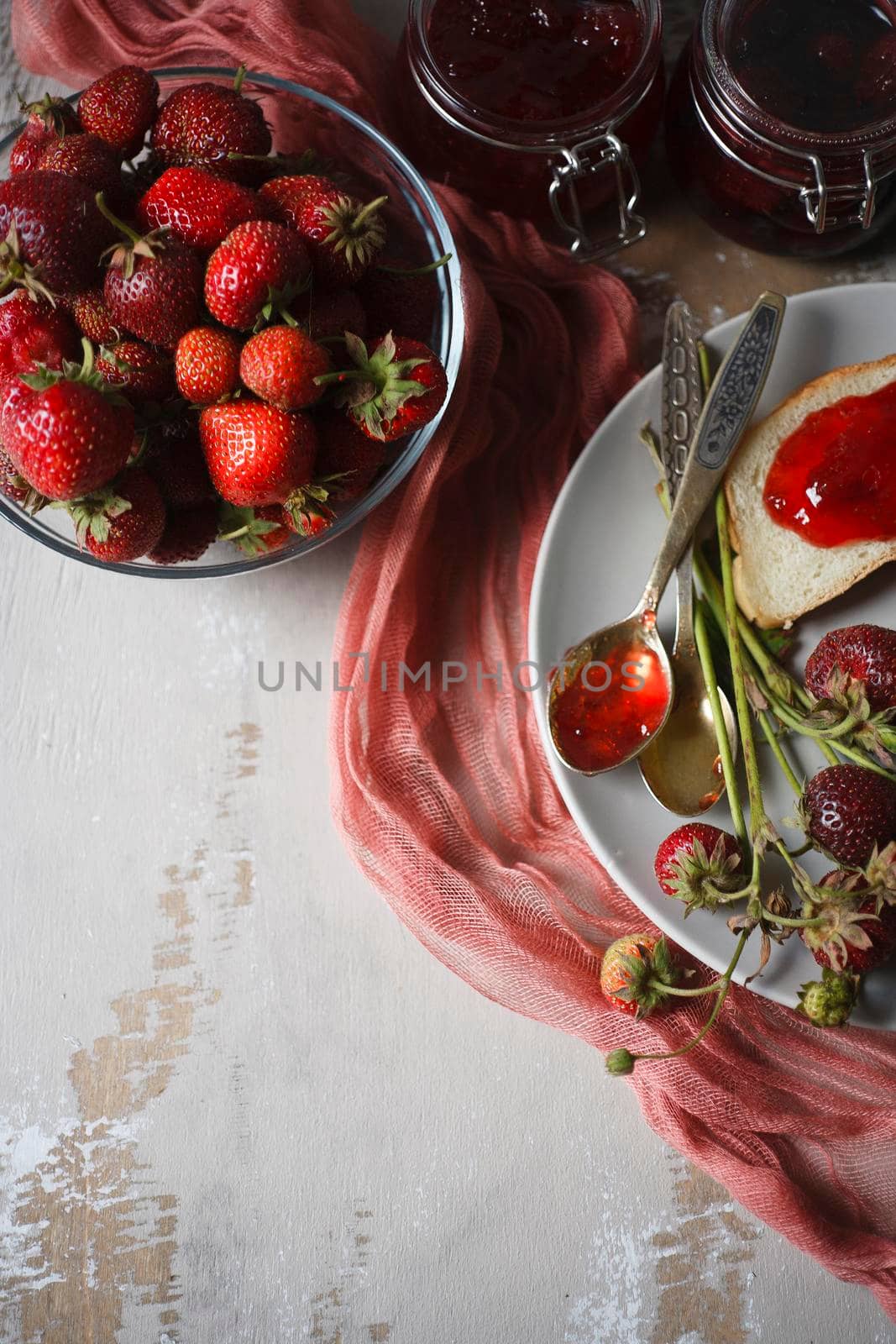 Summer breakfast concept with srawberry jam with bread and fresh harvested berries in a bowl on wooden rustic table, top view, flat lay, selective focus.