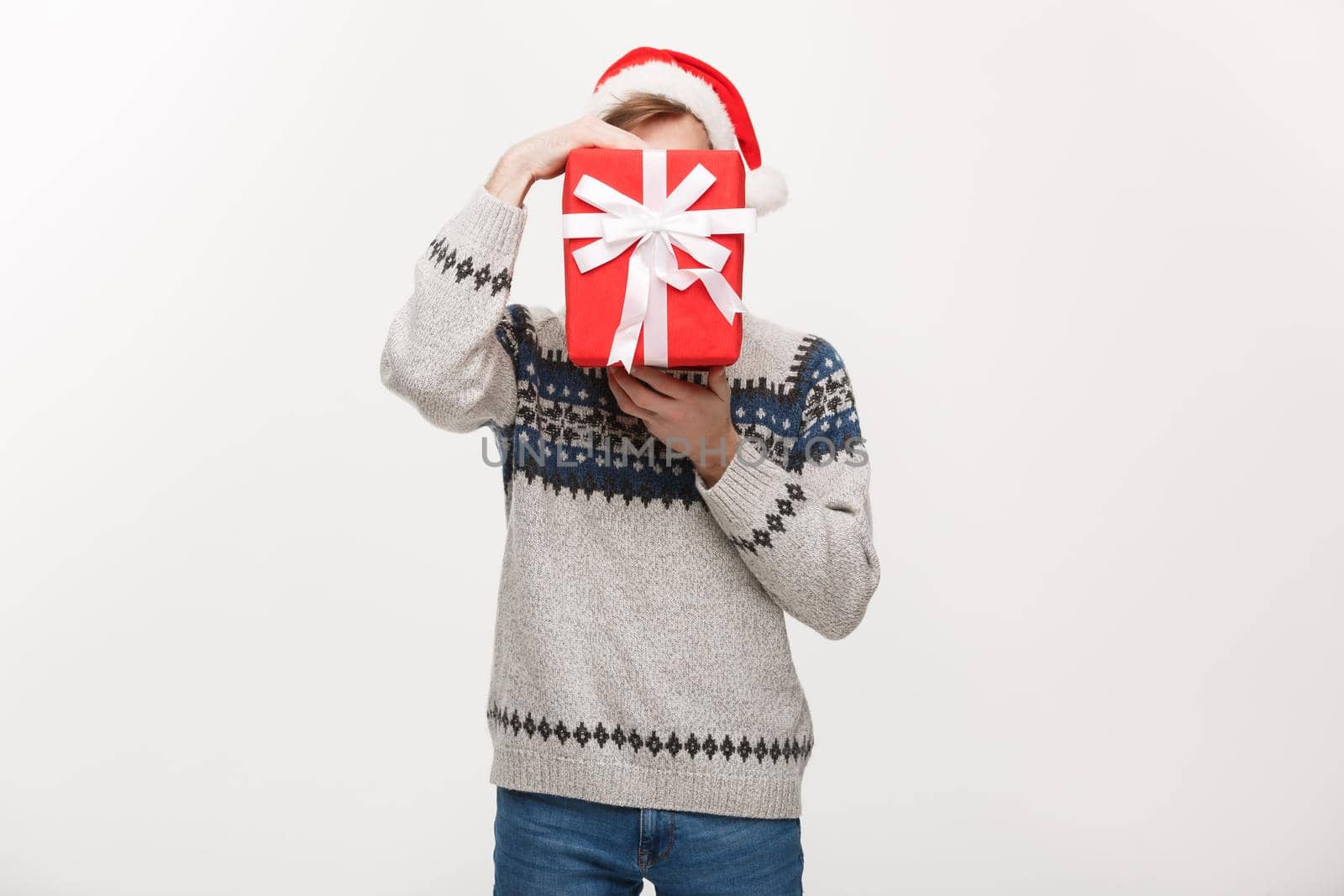 Holiday Concept - young handsome man hiding himself behind present.