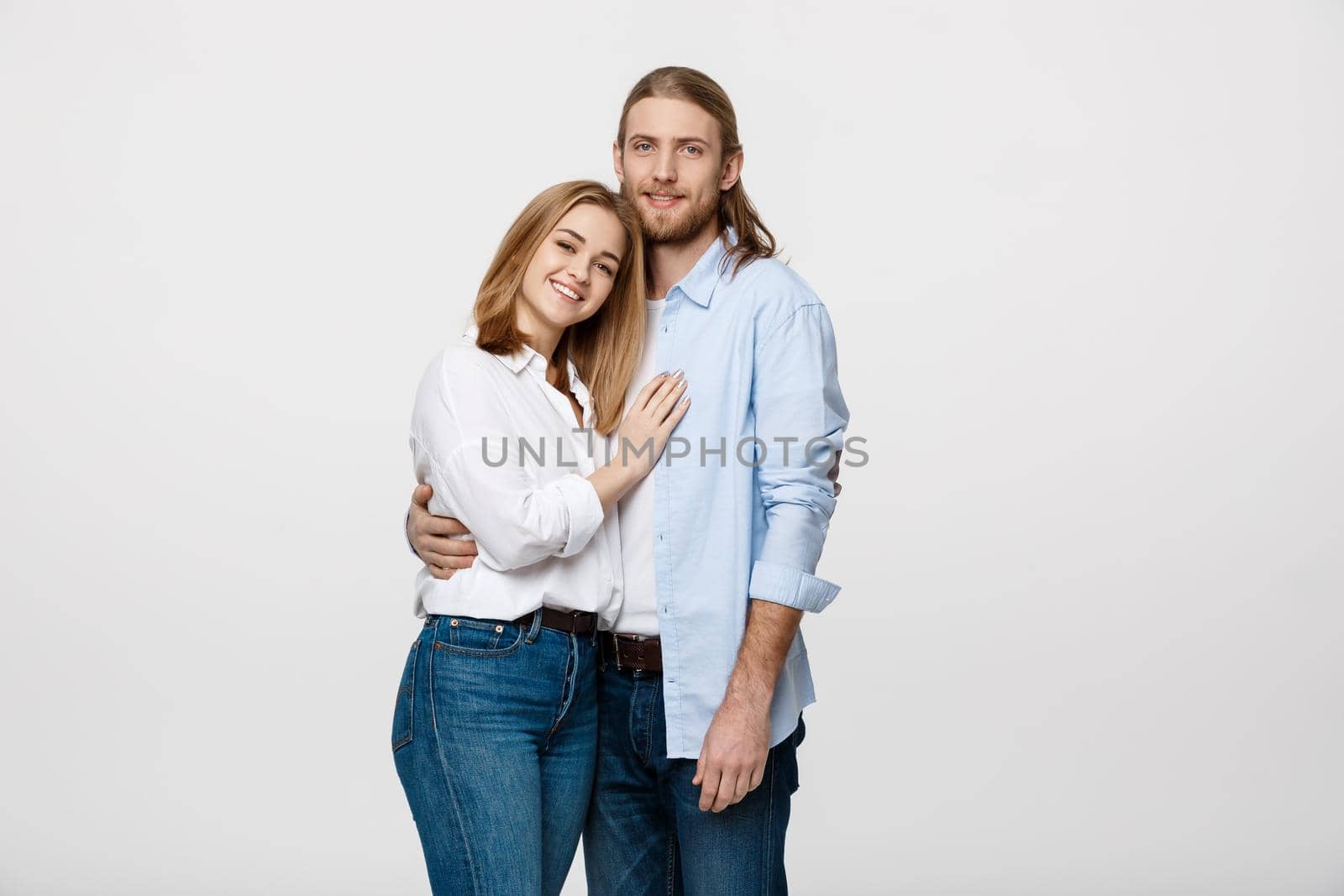 Portrait of cheerful young couple standing and hugging each other on isolated white background.