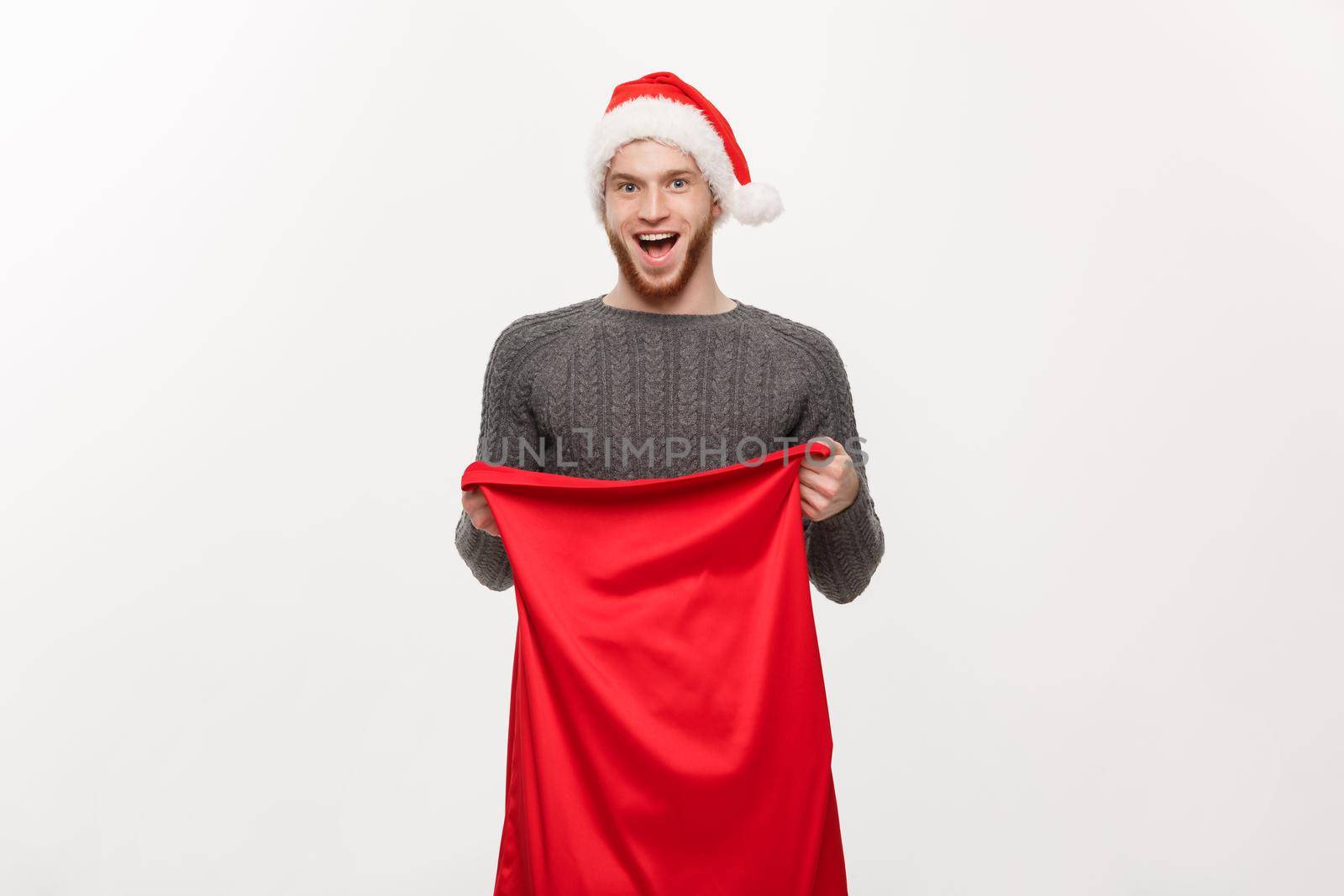 Christmas concept - Young beard handsome man exciting open santa big bag for present.