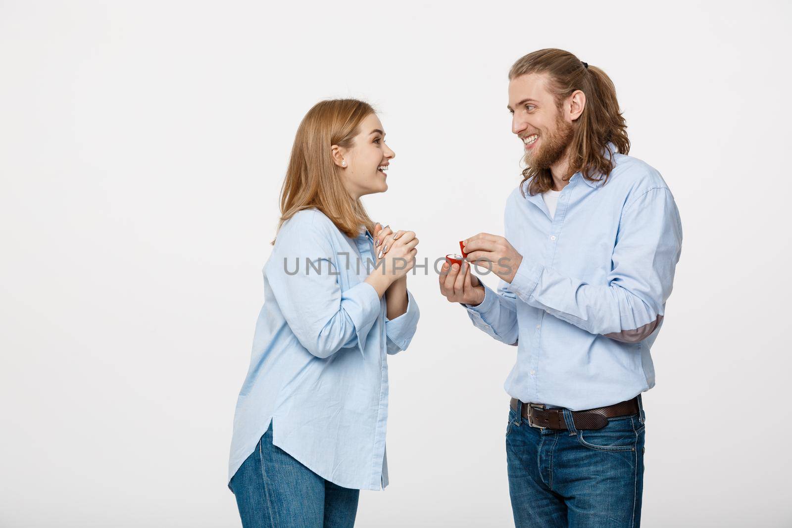 Proposal concept - Portrait of man showing an engagement ring diamond to his beutiful girlfriend over isolated white background .