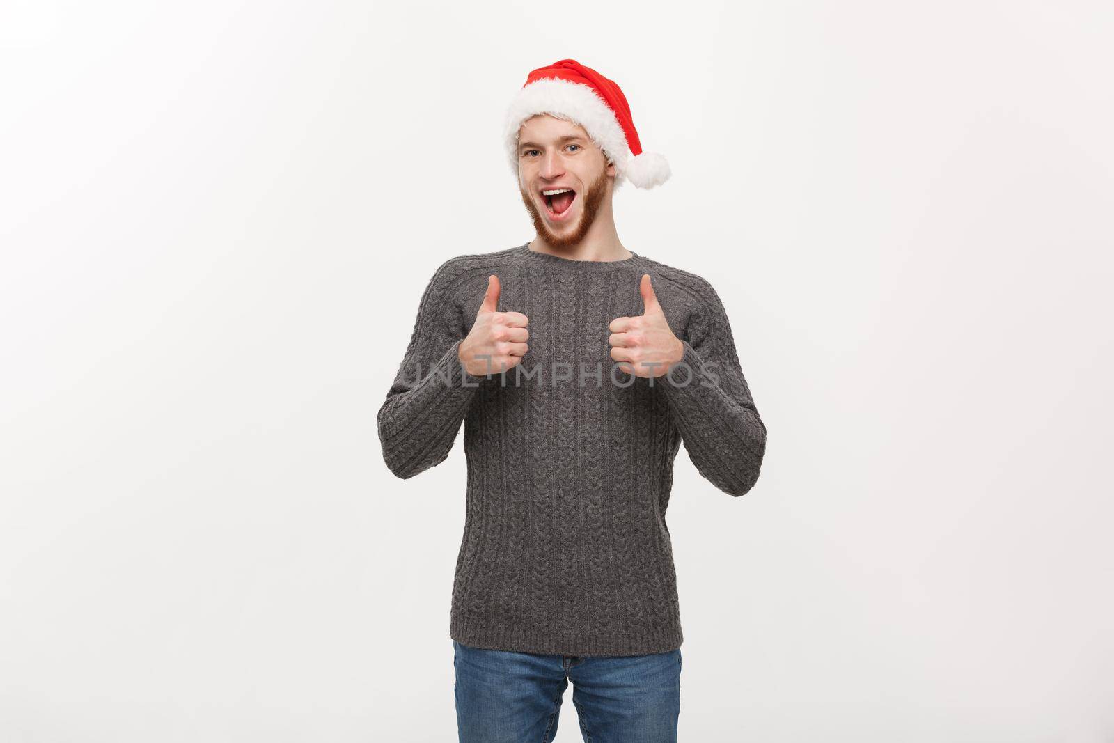 Holiday Concept - Young beard man in sweater giving thumb up to camera.