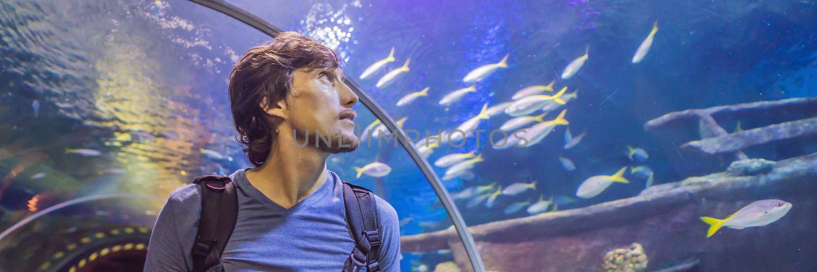 curious tourist watching with interest on shark in oceanarium tunnel. BANNER, LONG FORMAT