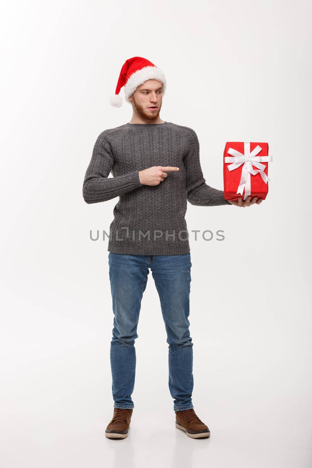 Christmas Concept - Happy young man with beard pointing finger present isolated on white background.