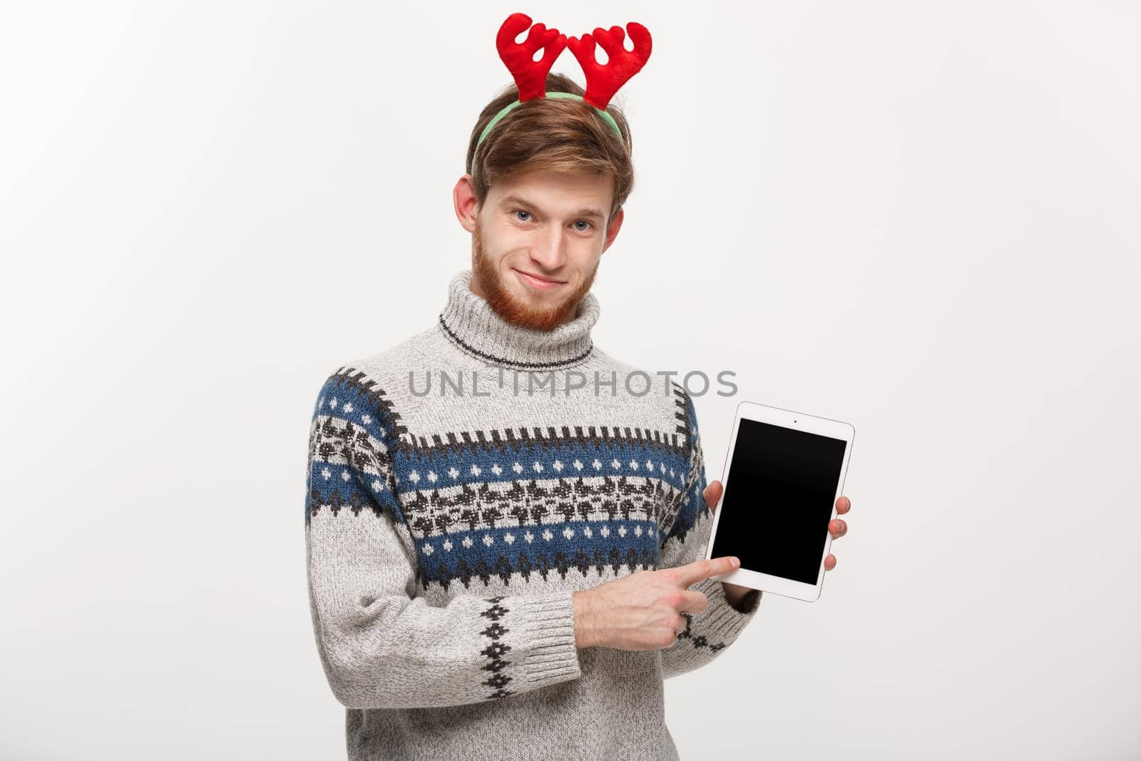 Holiday and Business Concept - Young handsome man showing tablet display and pointing finger presenting.