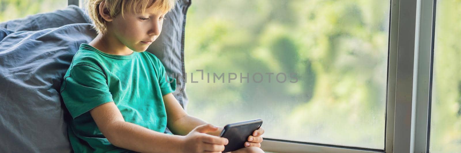 Little blond boy playing games on smartphone BANNER, LONG FORMAT by galitskaya