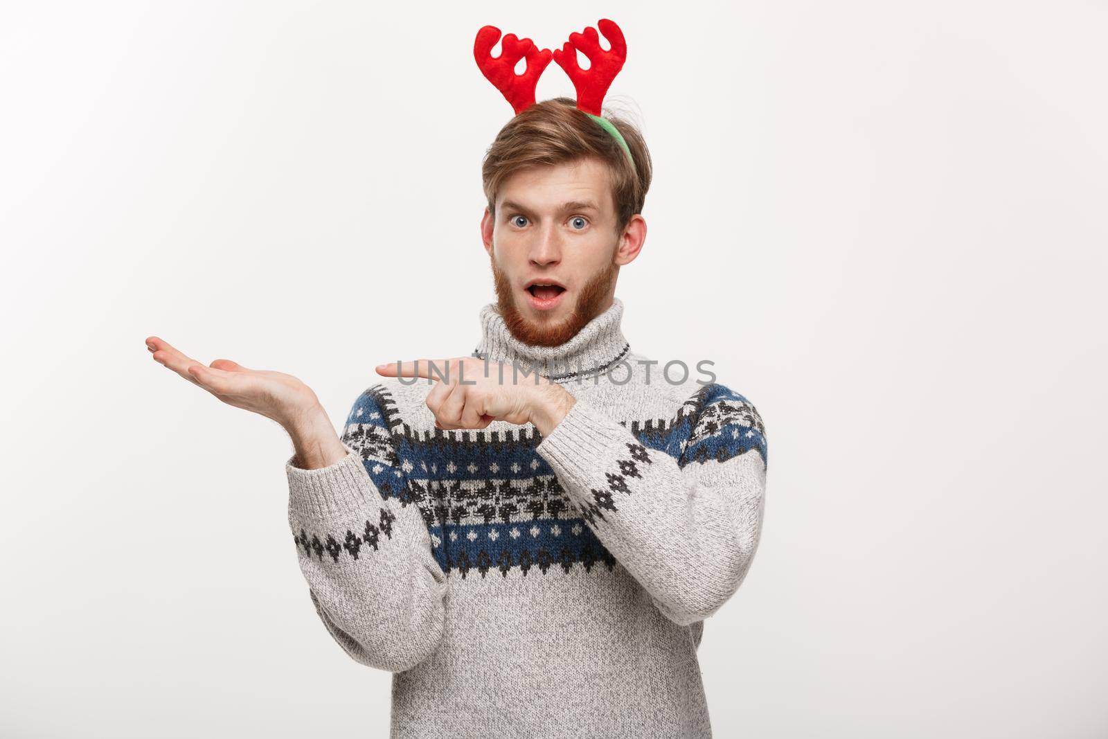 Holiday Concept - Young beard man in sweater enjoy playing and pointing hand on side