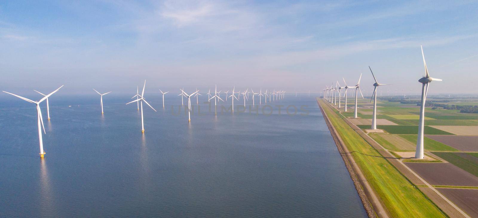 Windmill farm in the ocean Westermeerwind park, windmills isolated at sea on a beautiful bright day Netherlands Flevoland Noordoostpolder. Huge windmill turbines