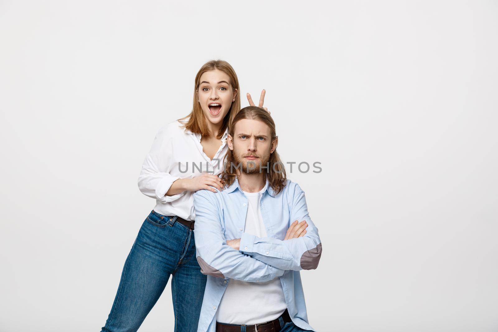 Portrait of lovely young couple showing peace or victory sign on white studio background by Benzoix