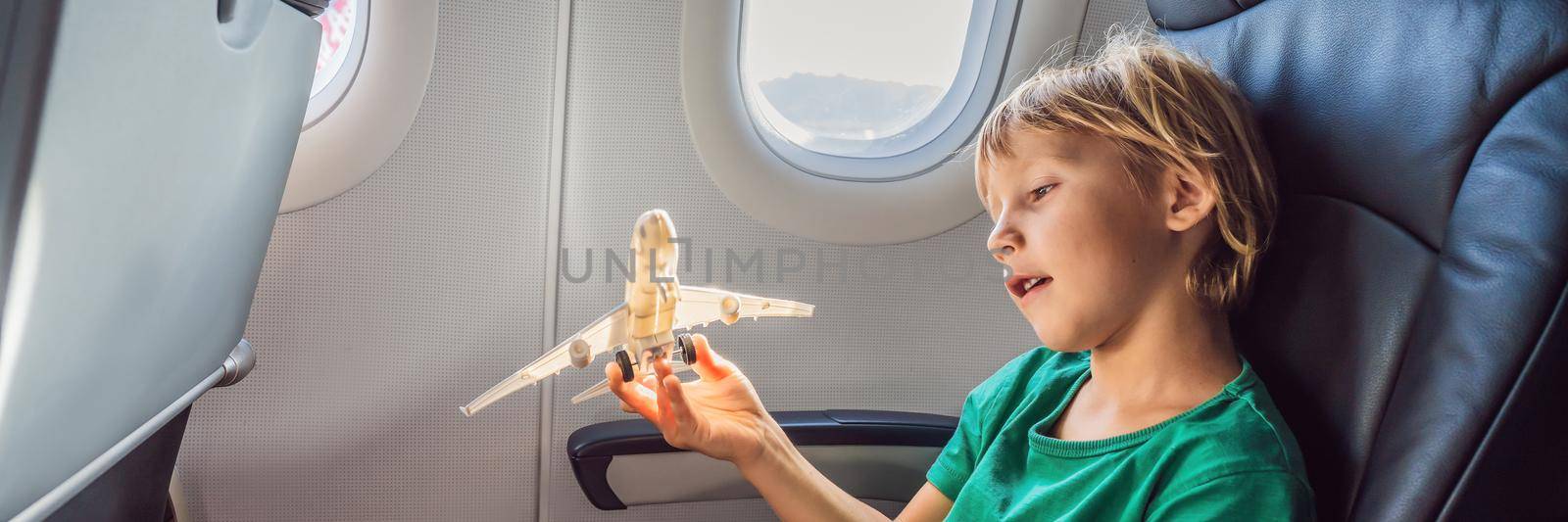 Little boy play with toy plane in the commercial jet airplane flying on vacation BANNER, LONG FORMAT by galitskaya