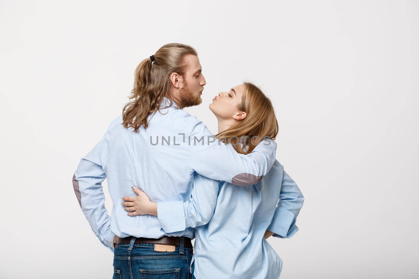 Young caucasian couple kissing over isolated white studio background