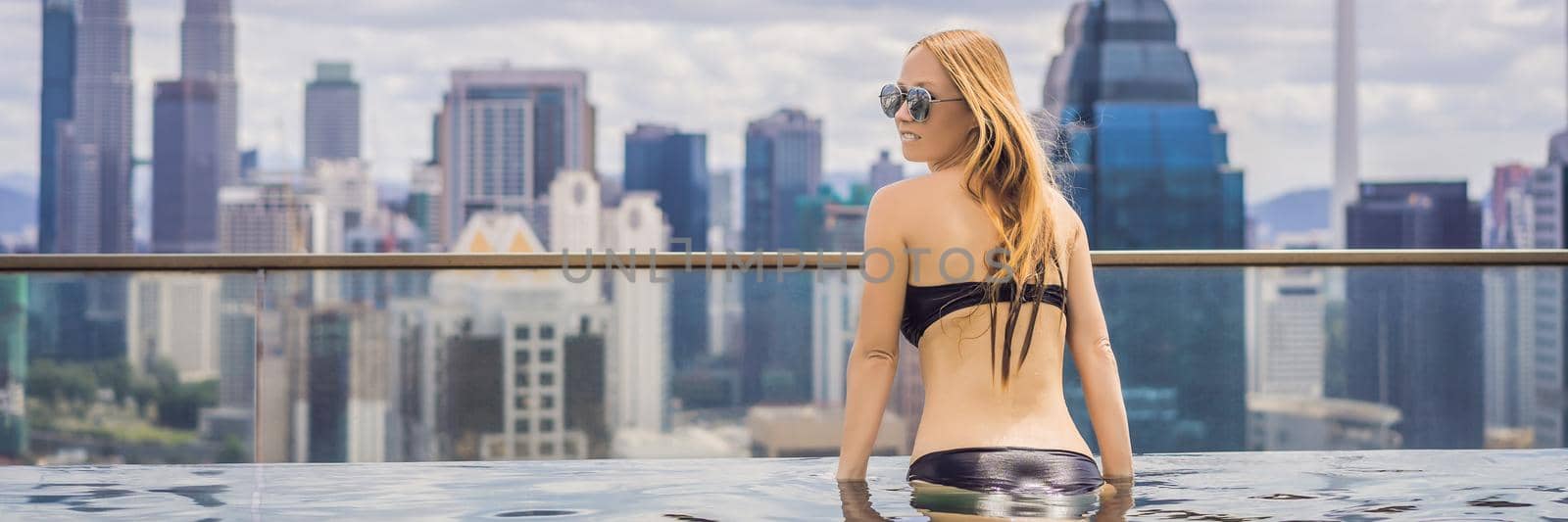 Young woman in outdoor swimming pool with city view in blue sky. Rich people BANNER, LONG FORMAT by galitskaya