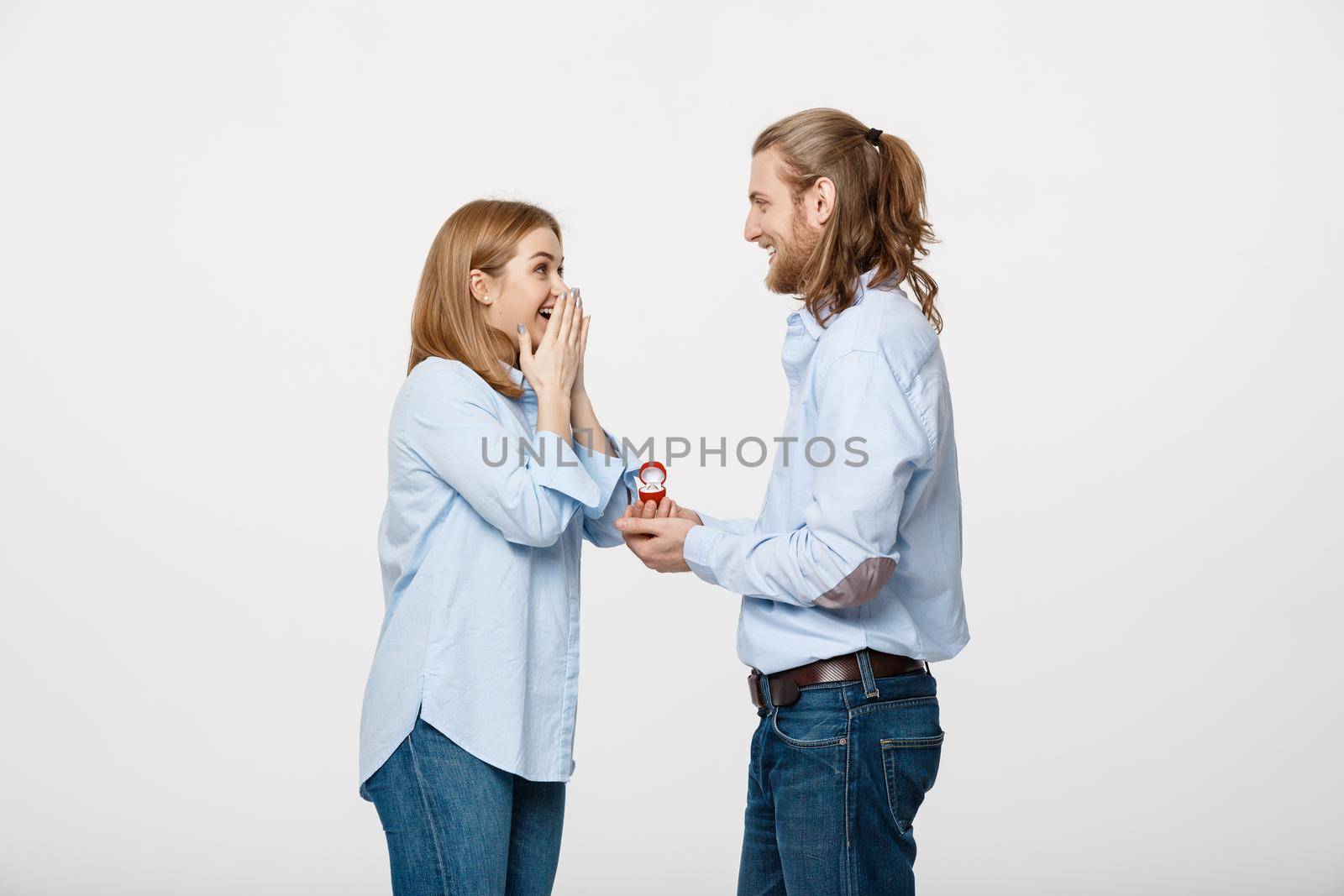 Proposal concept - Portrait of man showing an engagement ring diamond to his beutiful girlfriend over isolated white background .
