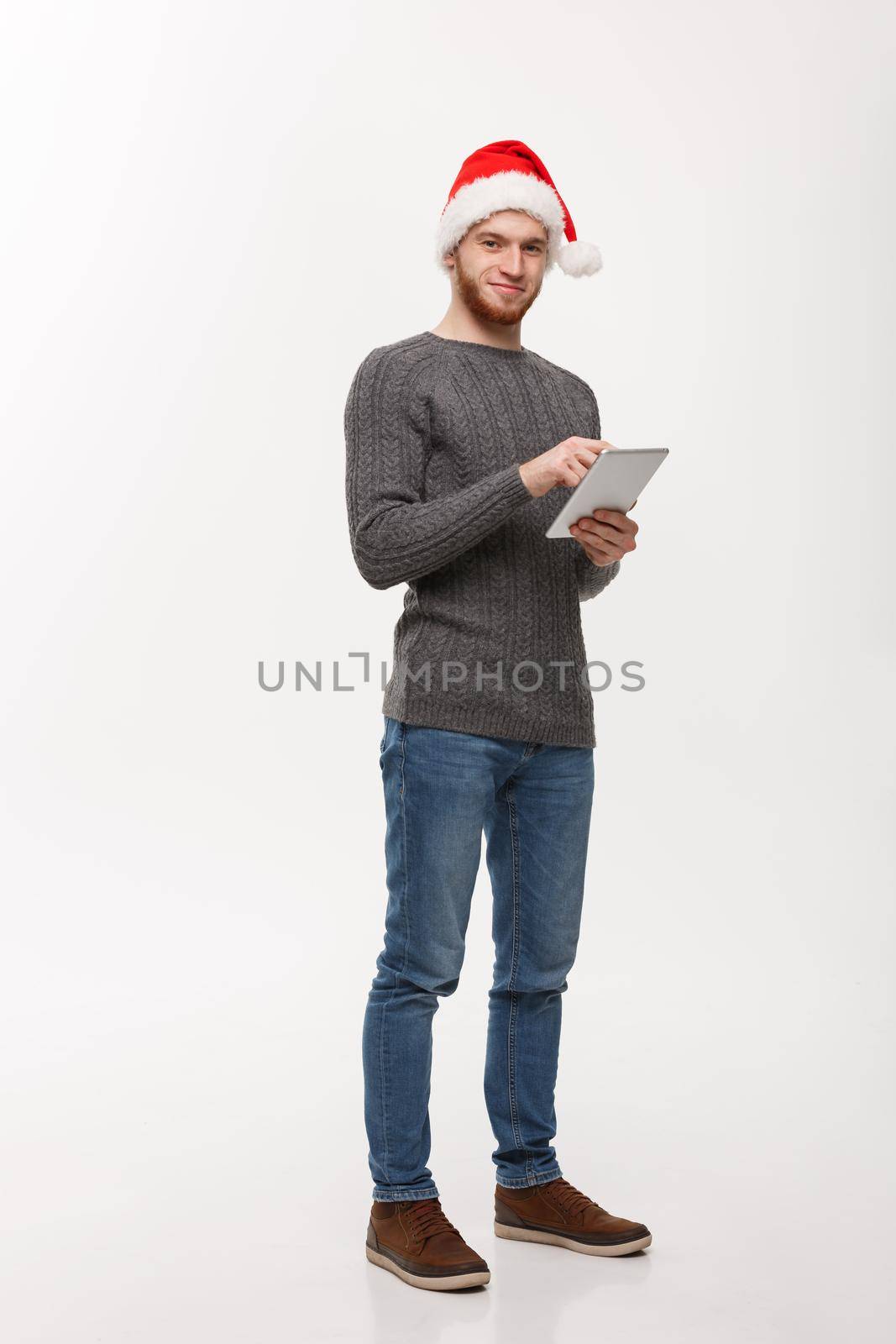 Holiday concept - Young beard handsome man working on digital tablet over white background. by Benzoix