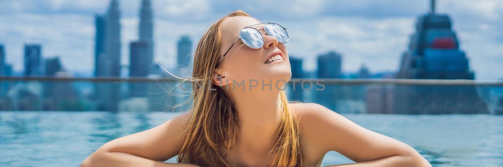 Young woman in outdoor swimming pool with city view in blue sky. BANNER, LONG FORMAT