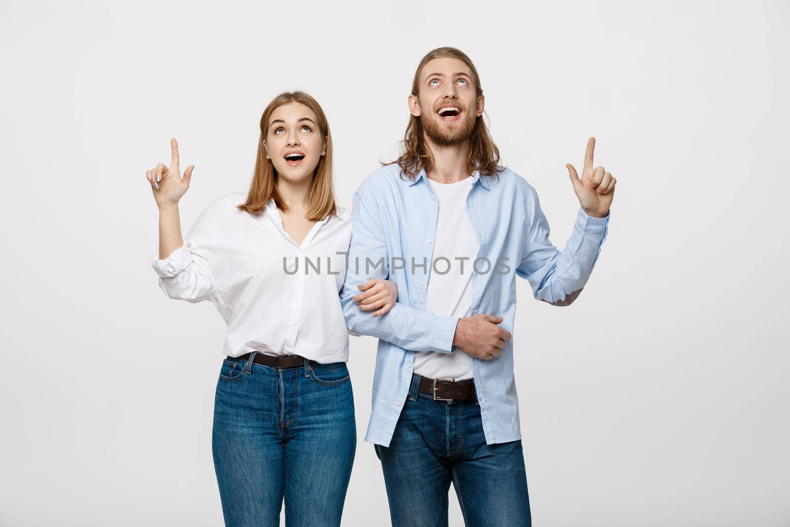 Portrait young happy couple love smiling embracing point finger to empty copy space, man and woman smile looking up, isolated over white background by Benzoix