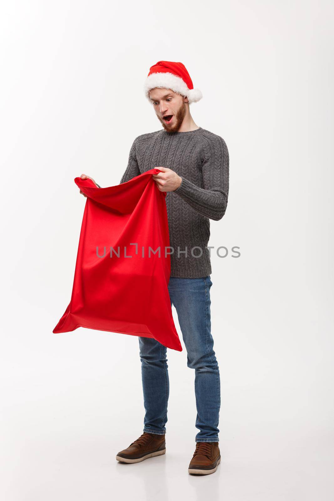 Christmas concept - Young beard handsome man exciting open santa big bag for present.