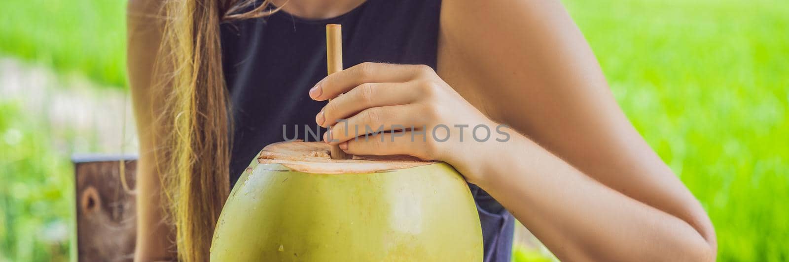 Young woman with fresh coconut cocktail in the background of a rice field BANNER, LONG FORMAT by galitskaya