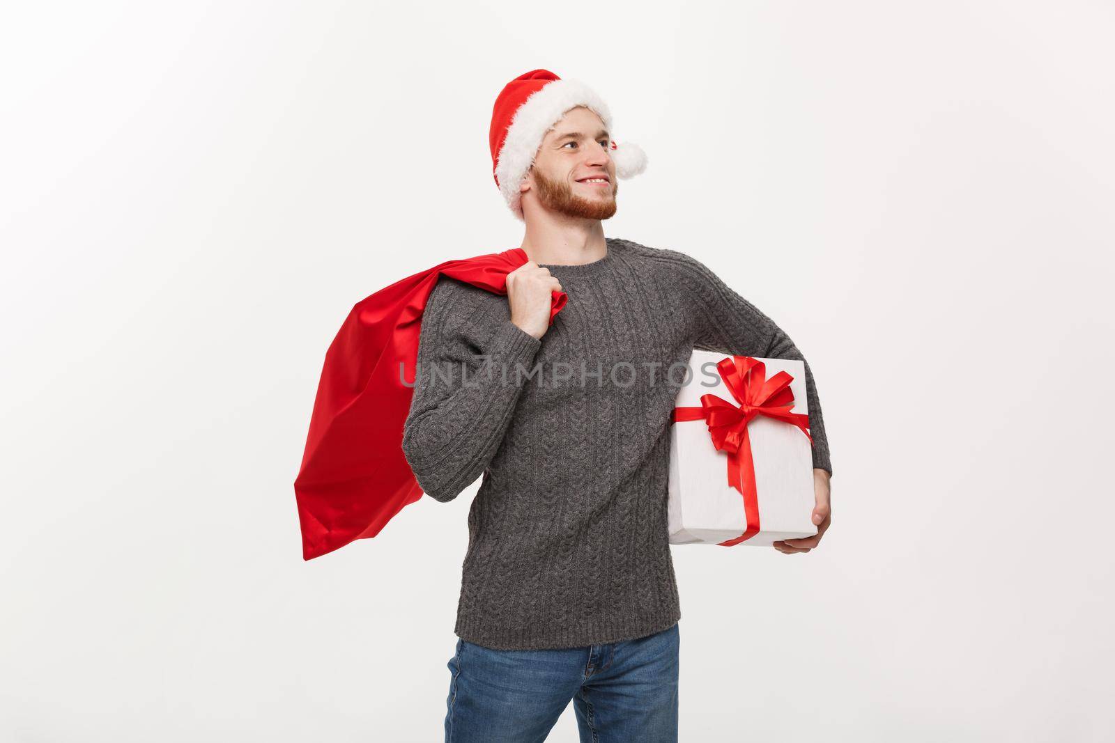 Christmas Concept - Young happy beard man holding santa bag and white present.