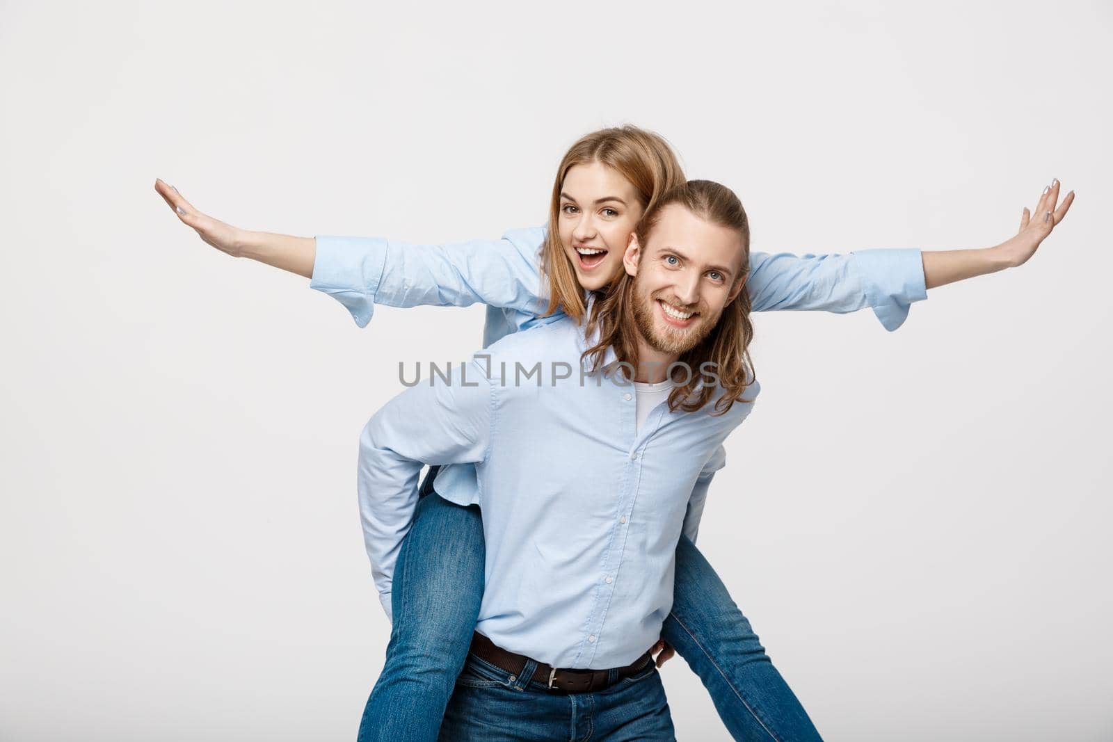 Portrait of smiling man giving happy woman a piggyback ride. by Benzoix