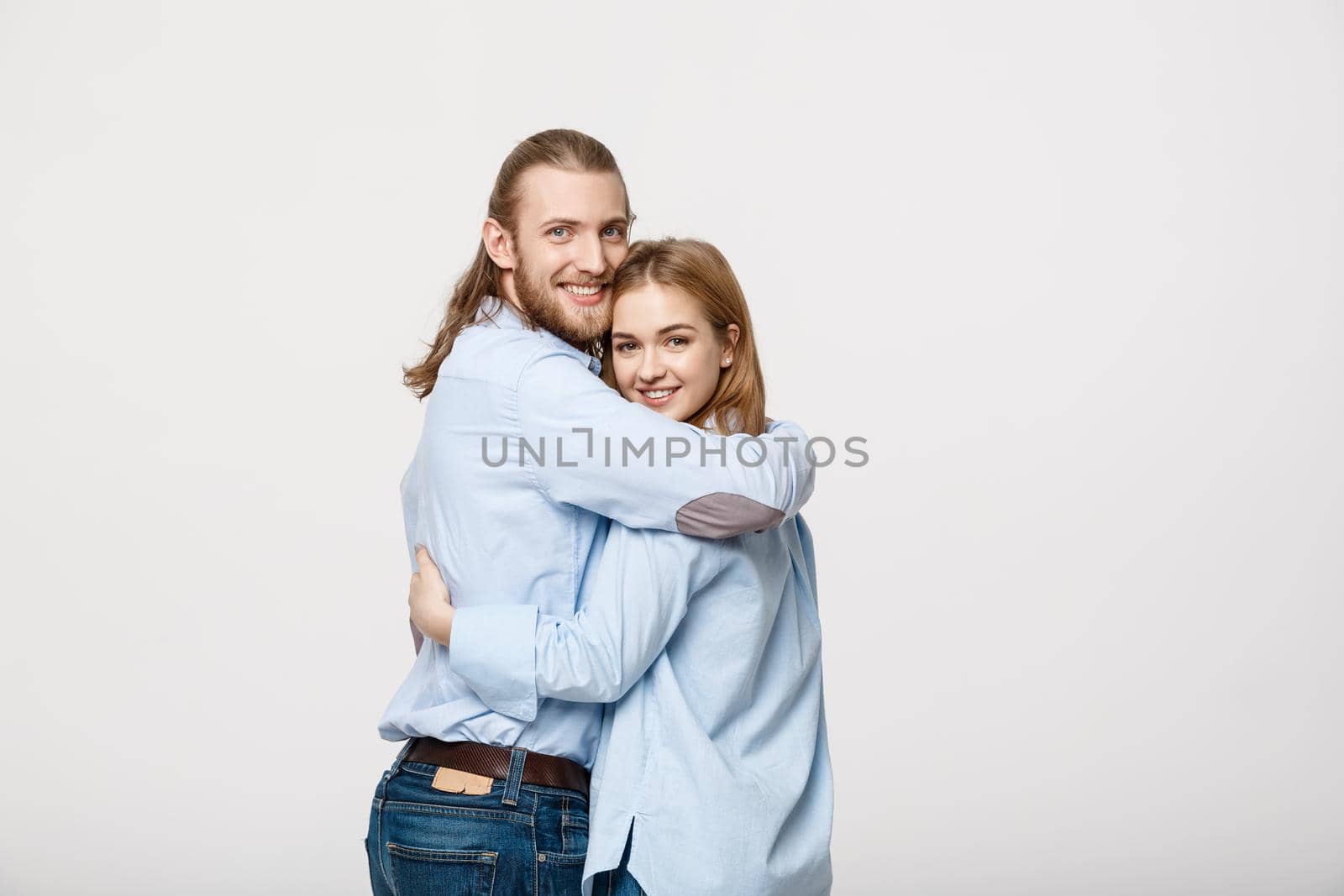 Portrait of cheerful young couple standing and hugging each other on isolated white background by Benzoix