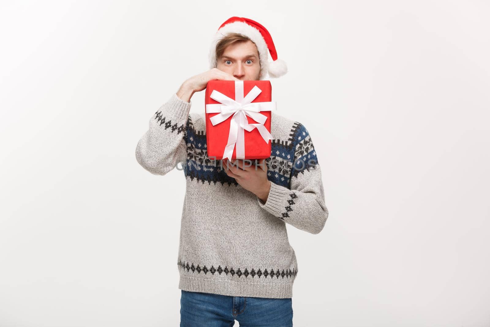 Holiday Concept - young handsome man hiding himself behind present.