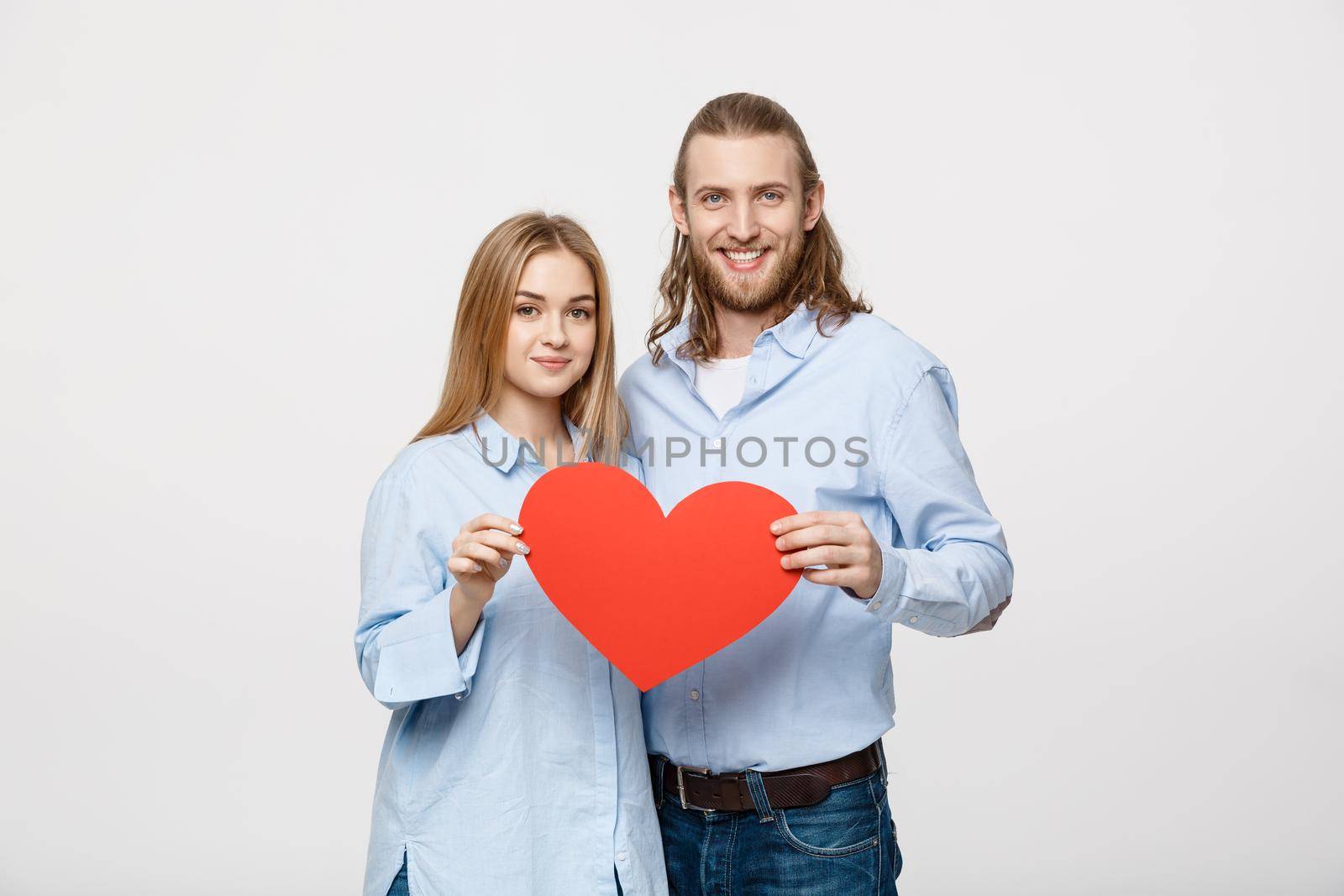 Portrait of young happy couple in love holding red paper heart. by Benzoix