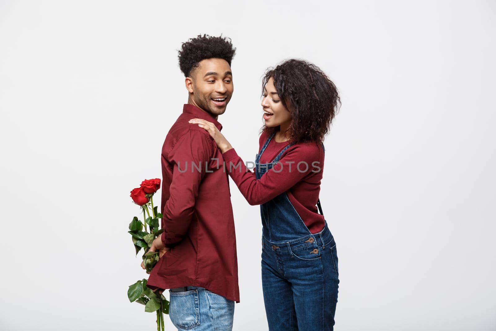 Beautiful elegant couple is hugging and smiling, on gray background. Girl is holding roses.