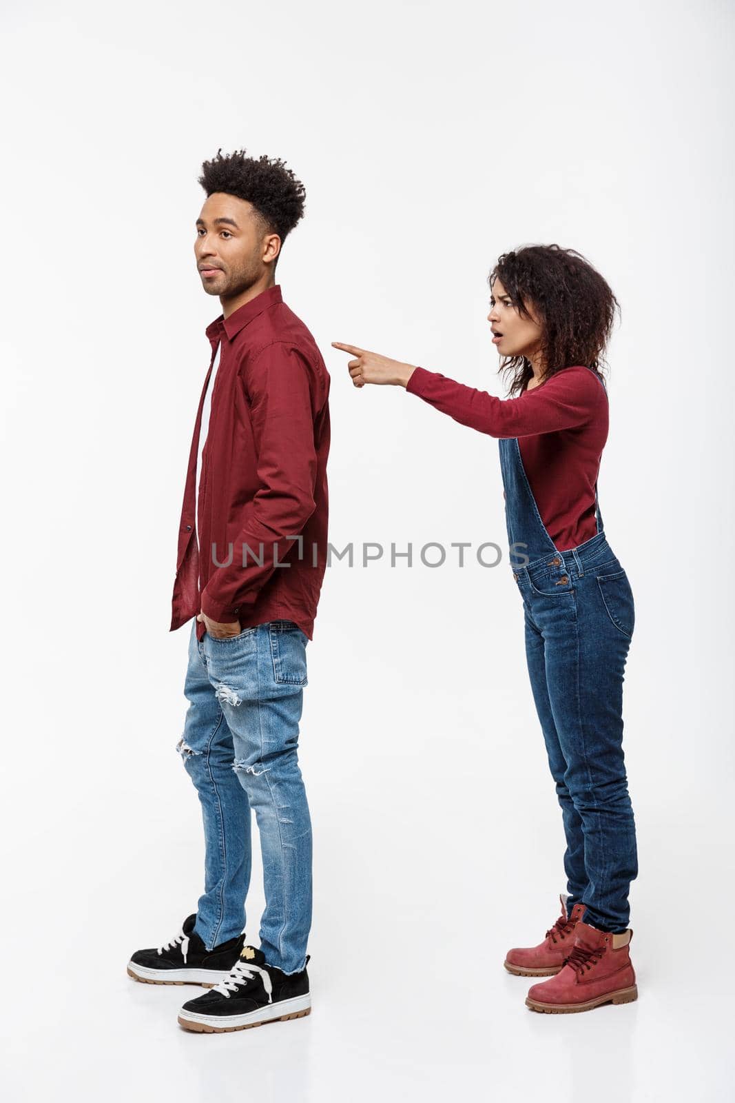 Studio shot of young angry woman pointing finger to her boyfriend with serious expression.