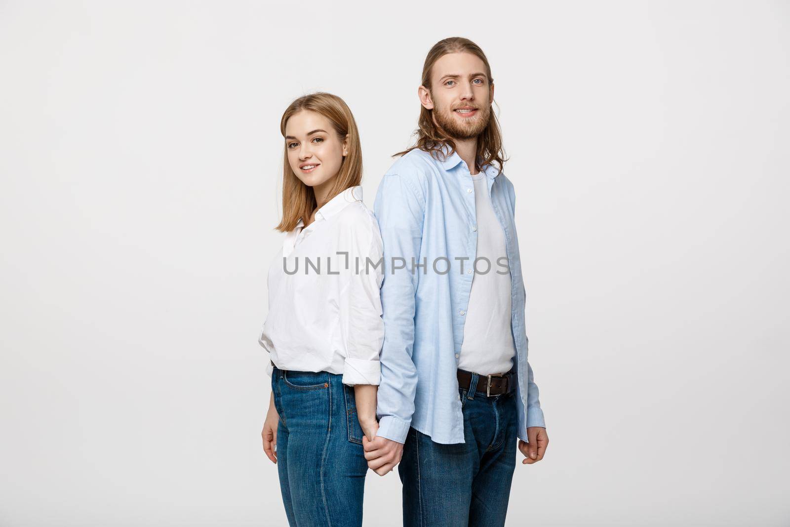 Cheerful happy man and woman with holding hands standing back to back. by Benzoix
