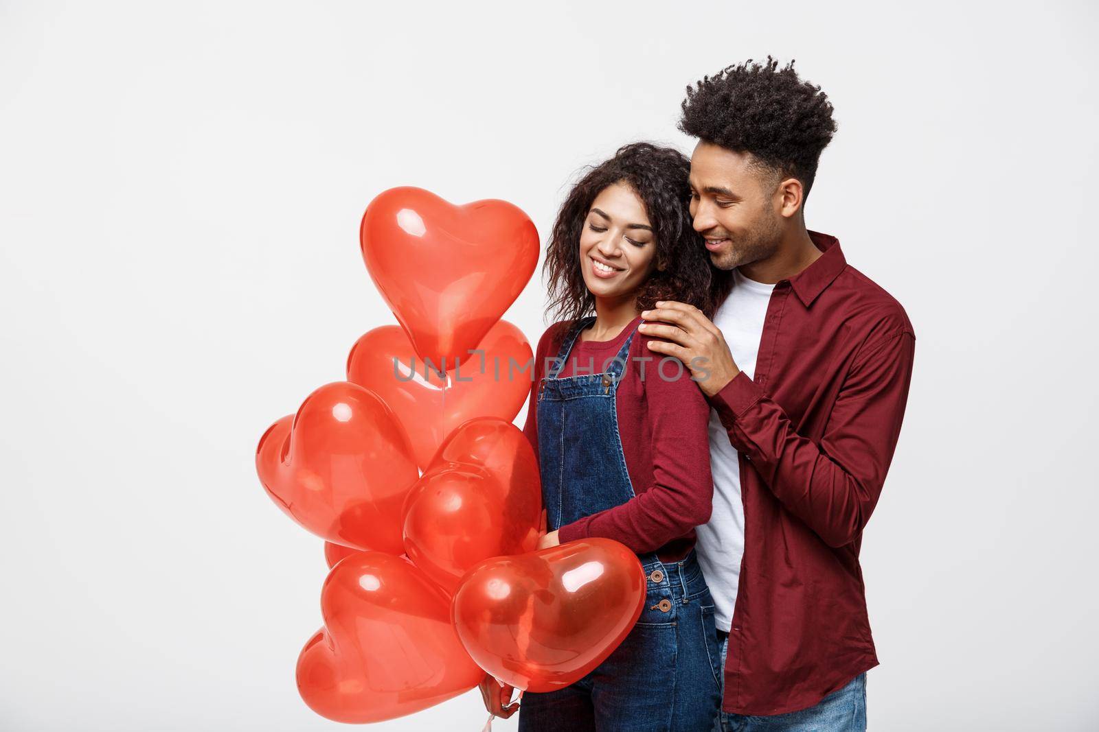 Close up attractive African American couple huging and holding red heart balloon