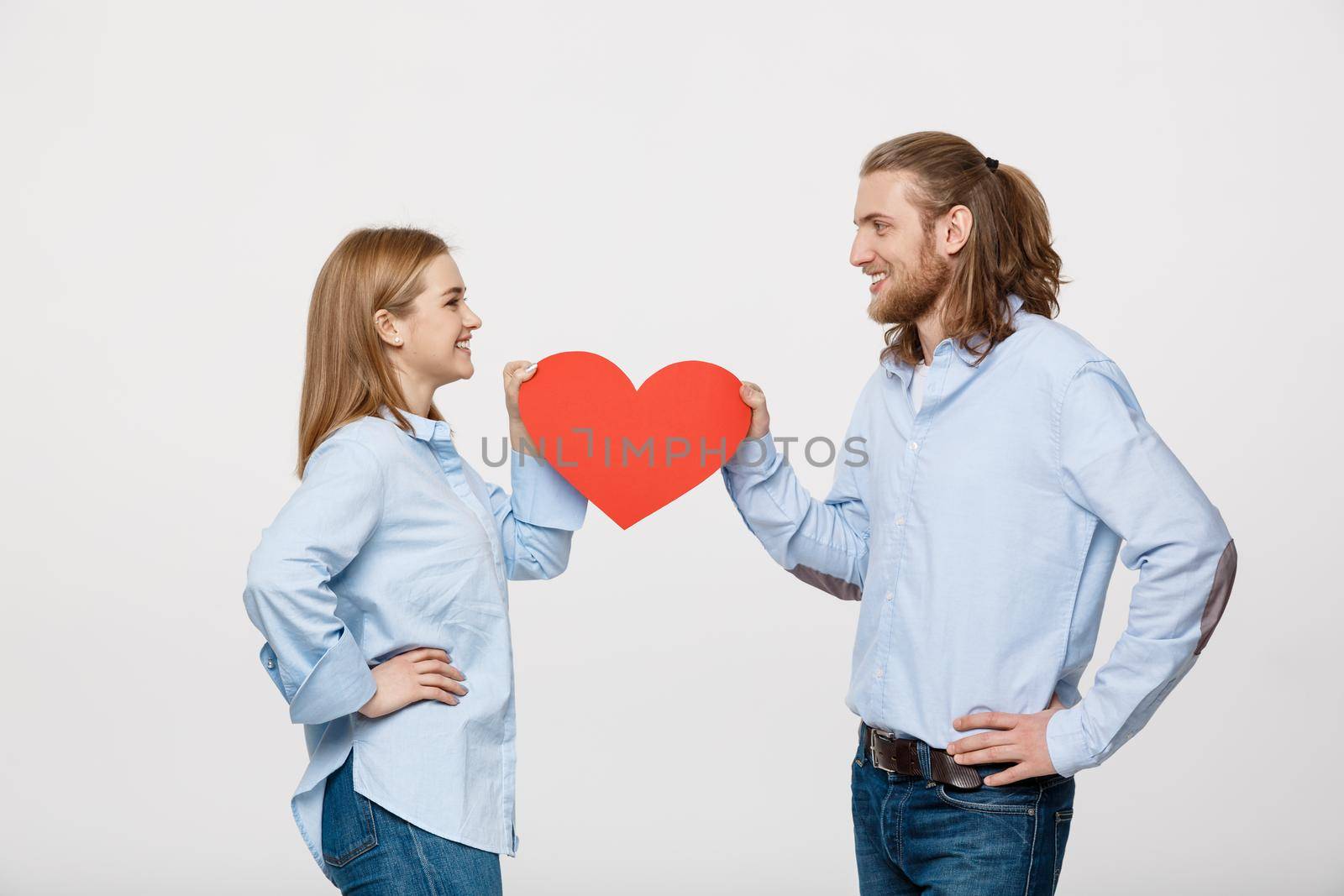 Portrait of young happy couple in love holding red paper heart