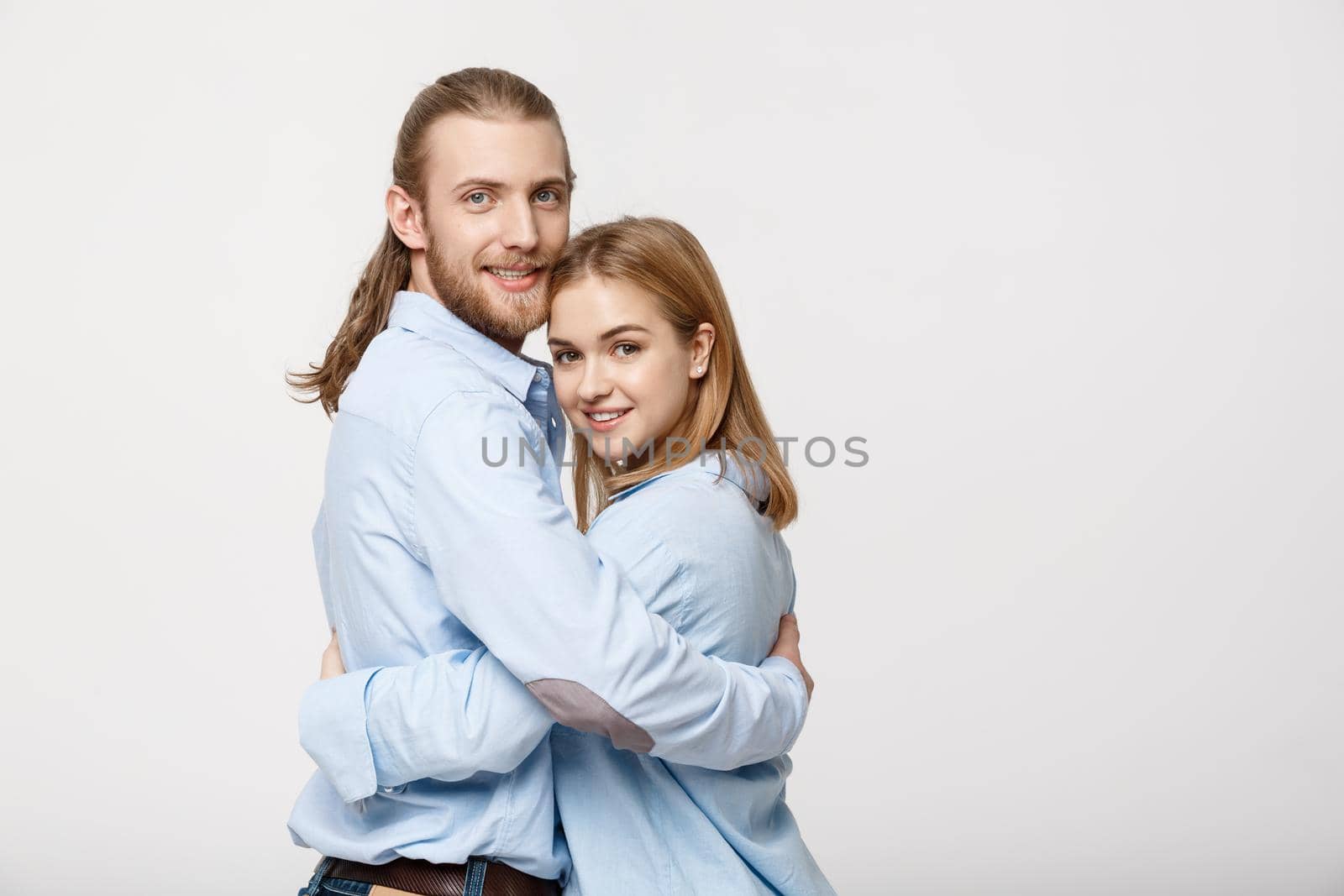 Portrait of cheerful young couple standing and hugging each other on isolated white background.