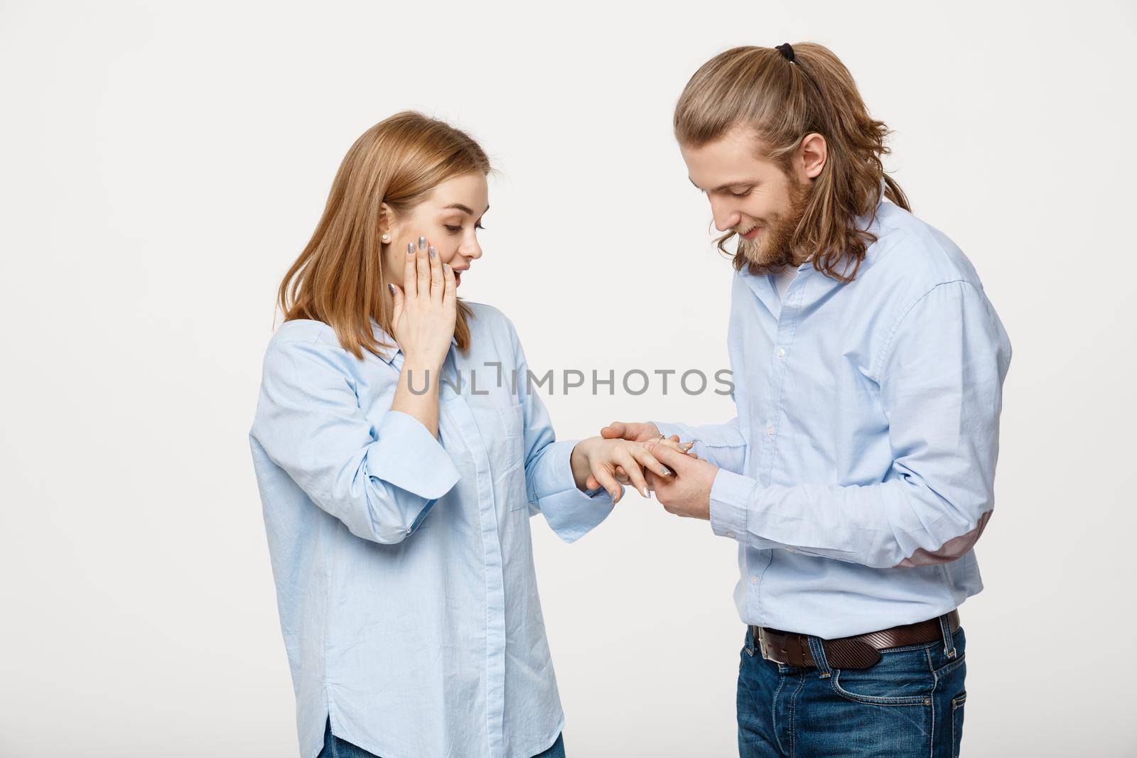 Portrait of Cheerful delighted handsome man wearing an engagement ring for her girlfriend over isolated white background.